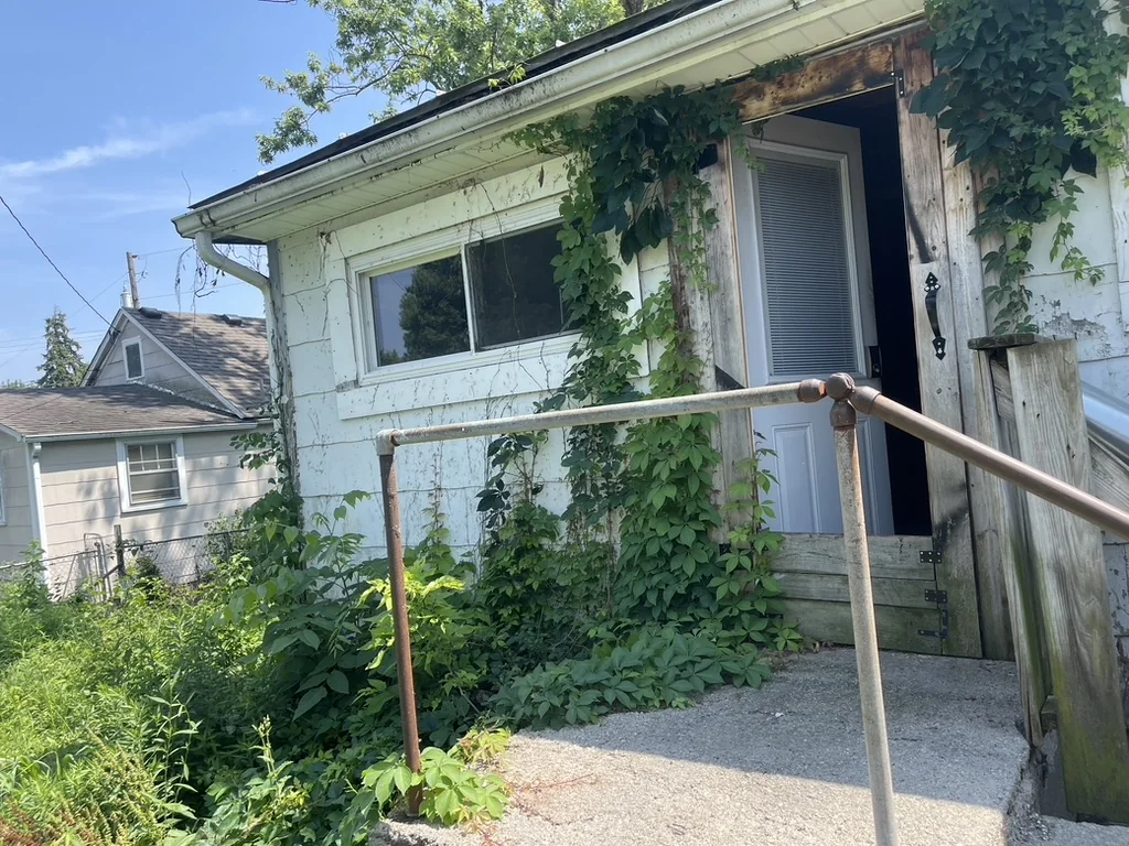 Overgrown exterior of the Greenville probate property before work began